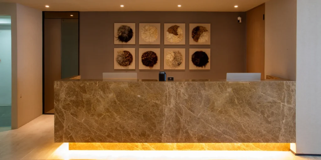 A modern, elegant reception area at Clinique de Paris with a welcoming concierge desk, designed to assist international patients seeking hair transplant and aesthetic treatments.